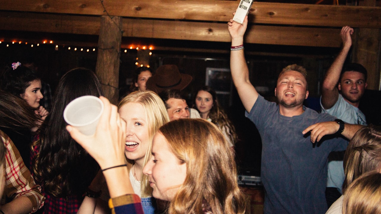 Guests crowded together at a house party, drinks raised